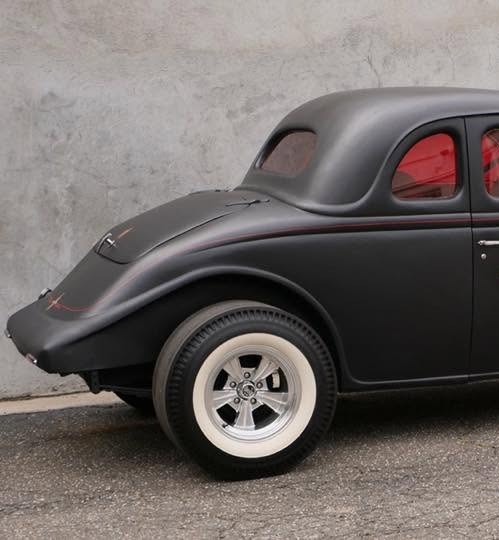Rear of a matte black five-window coupe, fitted with a Radir dragster slick