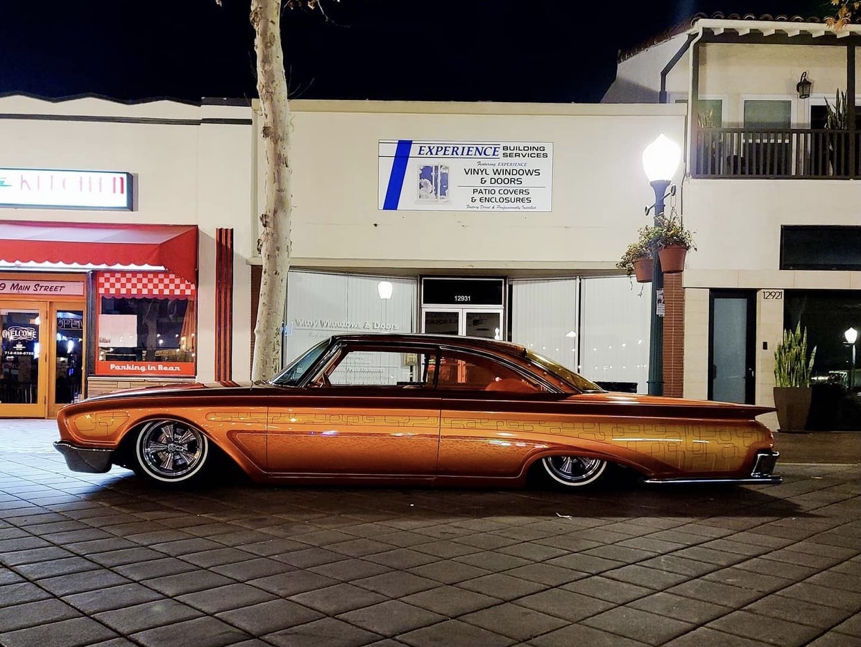 Copper 1960 Ford Starliner custom, lowered, on a city street at night