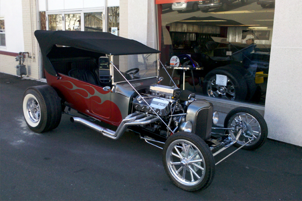 Red flamed T-bucket hot rod parked outside a shop